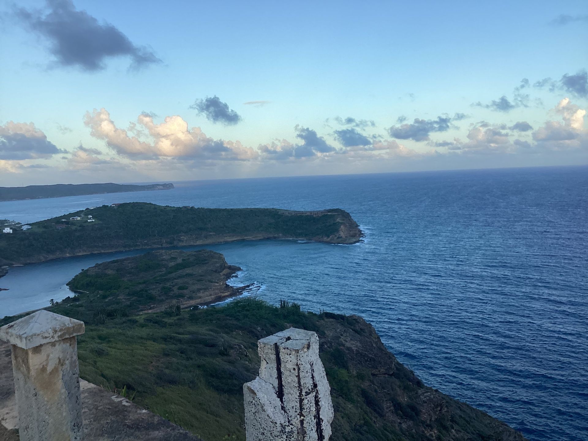 Scenic view of a coastal landscape with cliffs, ocean, and a partly cloudy sky.