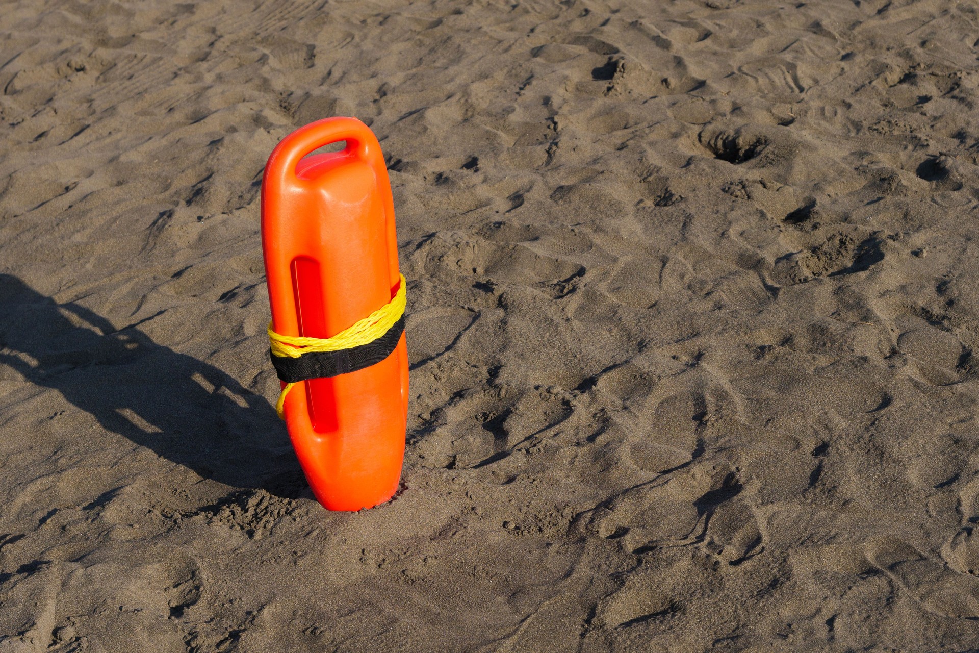 Lifeguard buoy secured on the sandy beach, ready for summer activities