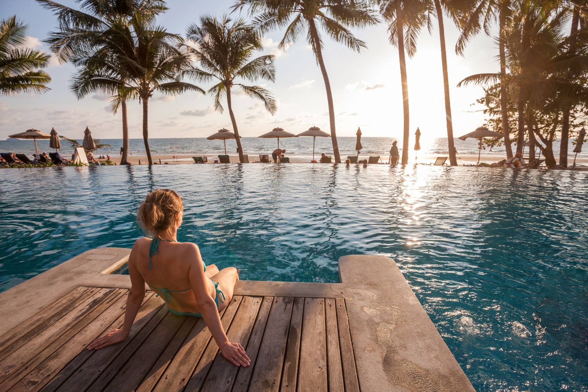 beach, woman enjoying sunset in luxury hotel near swimming pool