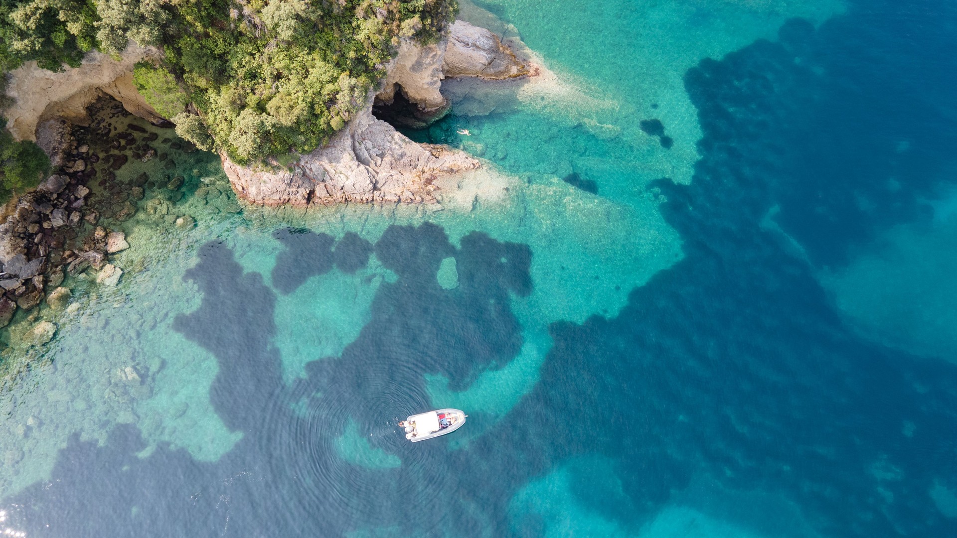 Seascape with boat near beach. Aerial view of floating boat on blue sea at sunny day. Aerial view of speed boat anchoring next to reef. Bird eye view, water sport theme.